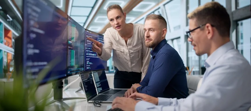 Colleagues collaborating around monitors in an operations room